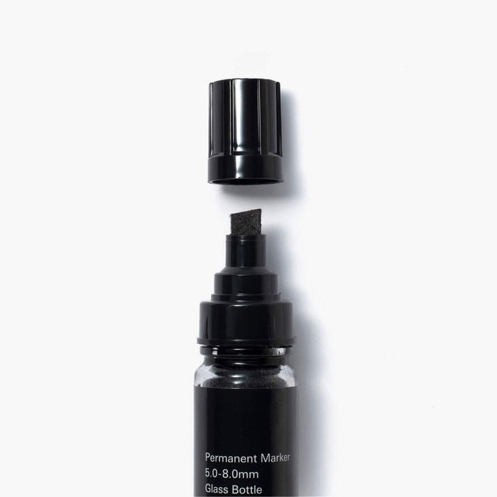 Chisel tip permanent marker with glass bottle on a white background