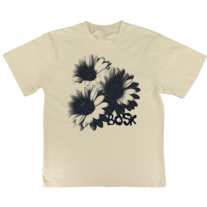 The Floret Tee by Other is an oversized men’s t-shirt in a cream off-white shade, crafted from heavyweight cotton. It features a bold black graphic print of three large daisies clustered together, with “BOSK” in graffiti-inspired black text beneath the flowers. The shirt is displayed laid flat on a white background.