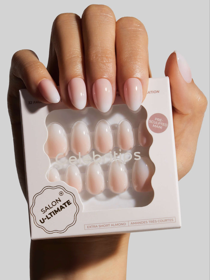 Hand holding a box of 'Salon Ultimate' press-on nails with neatly manicured nails in the background.