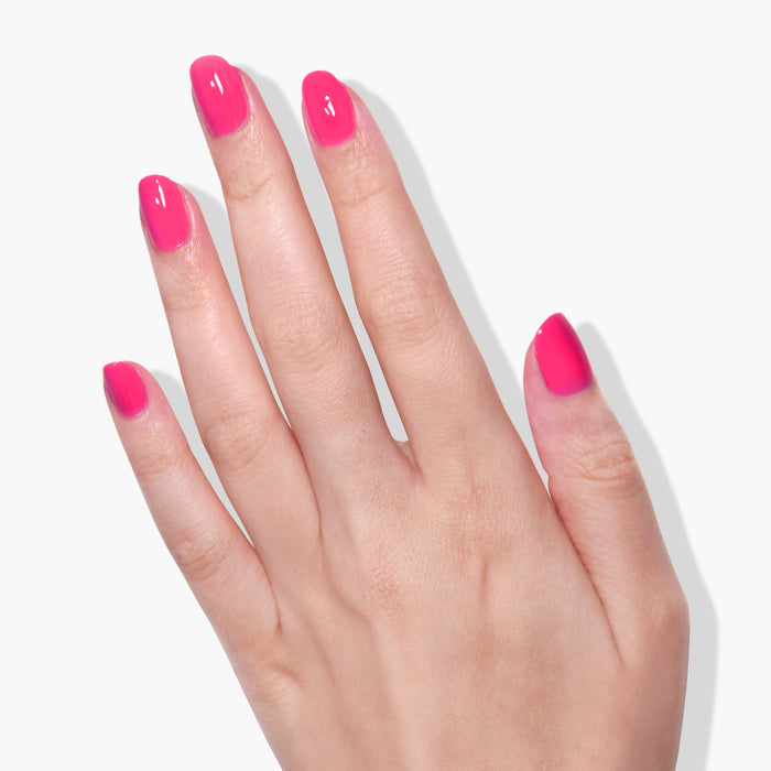 A hand with short, neatly manicured nails painted in LONDONTOWN's bright pink "Fruit Tella" cruelty-free polish, shown against a plain white background.