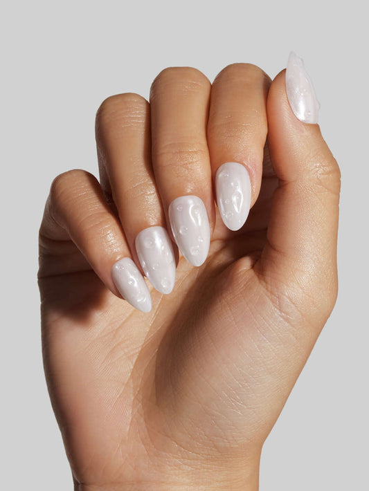 Hand with white nail polish on a plain background