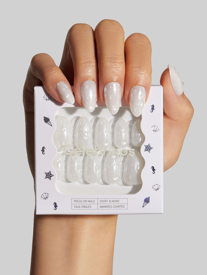 Hand holding a package of Glazing Drops press-on nails with a plain background