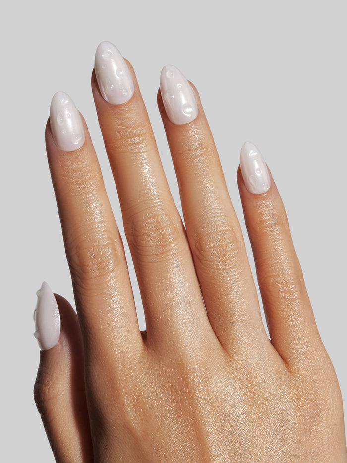 Hand with light pink nail polish on a plain background