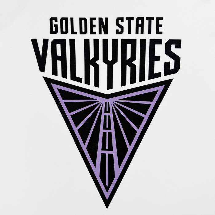 The image features the logo for "Golden State Valkyries" on a classic fit t-shirt named Golden State Valkyries Primary Tee by GSV. It boasts bold black text above an inverted triangle with a stylized purple wing outline, set against a crisp white 100% cotton backdrop.