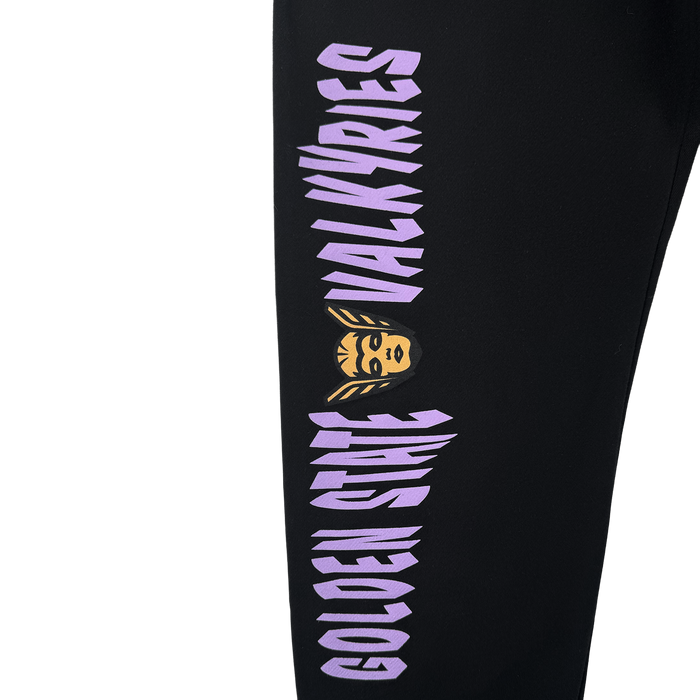 The GSV Renowned Pant by GSV is a black fleece sweatpant with bold, vertical purple "GOLDEN STATE VALKYRIES" text and a yellow Valkyrie face with winged helmet featured between the words.