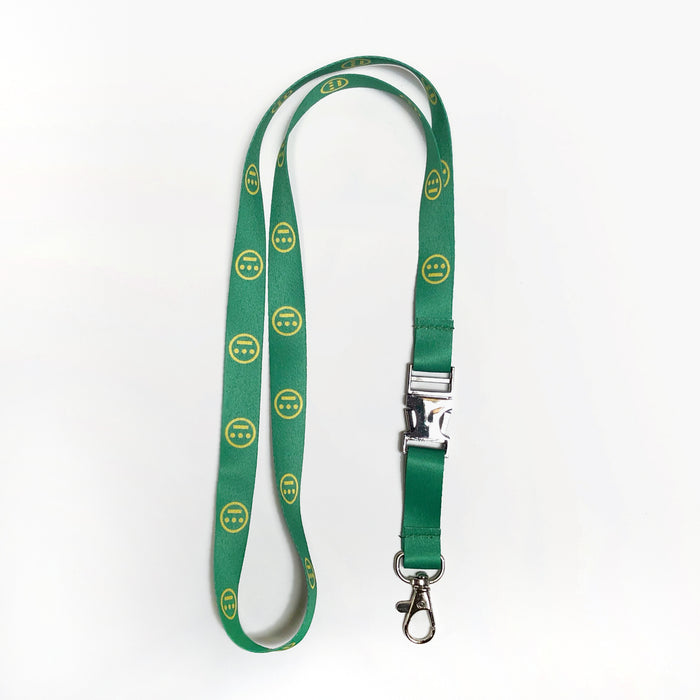 The Hieroglyphics Hiero VIP Lanyard features a vibrant green design adorned with yellow smiley face patterns. It comes equipped with a silver clasp and buckle, as well as a metal swivel hook for easy attachment of your key chain. The plain white background highlights the lanyard’s striking appearance.