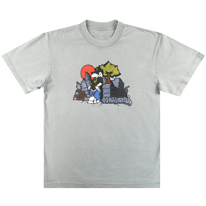 The Oaklandish Highroller Tee is a vintage grey heavy-weight cotton shirt with a cartoon-style black-and-white wolf by ruins and a tree, set against an orange-red sun. The classic fit design is centered on the chest for a timeless look.