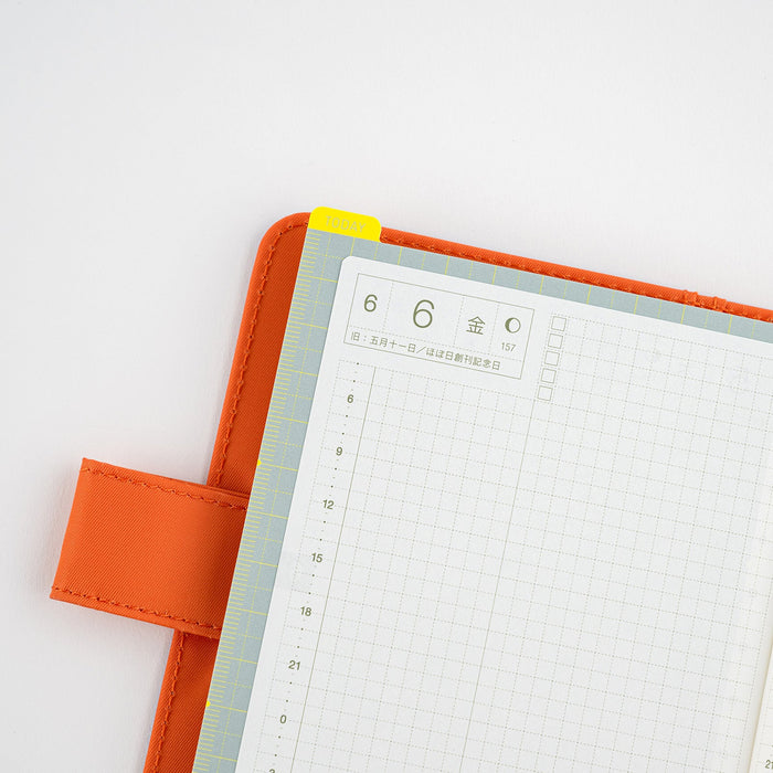 Hobonichi planner with gray pencil board in orange cover on light background