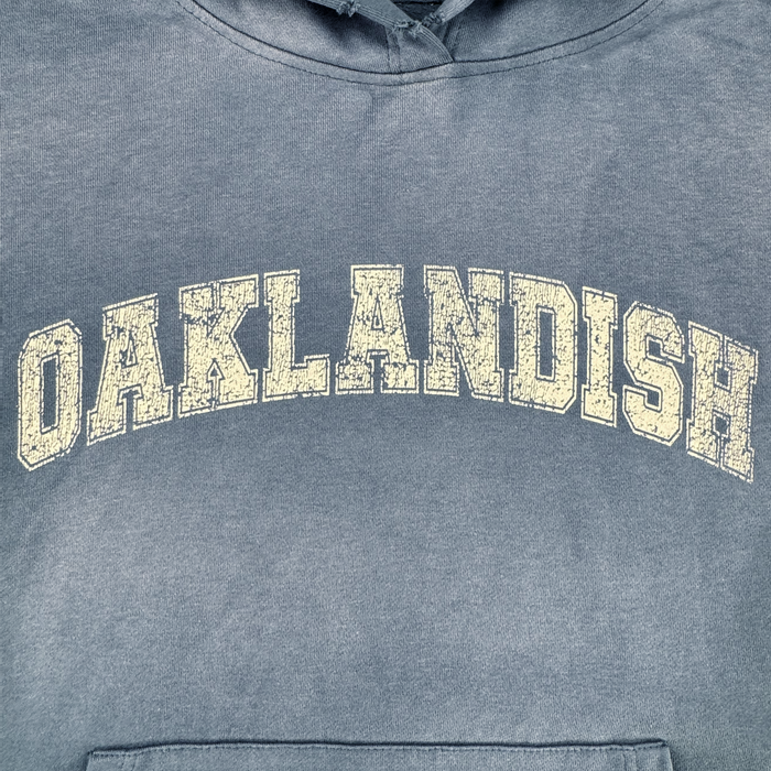 The Homage Hoodie by Oaklandish is a faded blue, 100% cotton pullover with "OAKLANDISH" in bold varsity letters and a worn print for a vintage vibe—a standout piece in men’s outerwear.