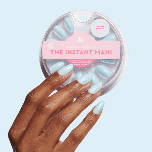 Hand with Honest & True | Almond | Medium serene blue medium almond shaped press-on nails on dark skin tone against light blue background