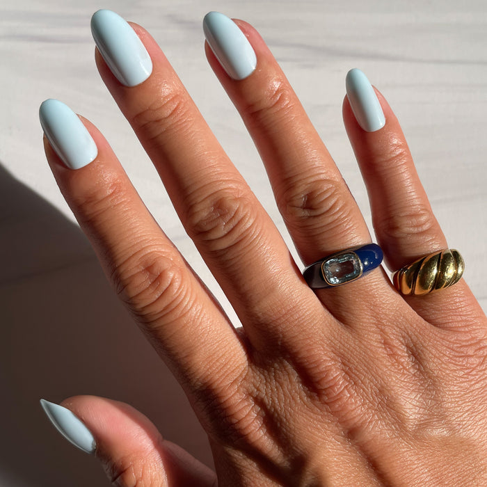 Hand with Honest & True | Almond | Medium serene blue medium almond shaped press-on nails and gold rings in natural light
