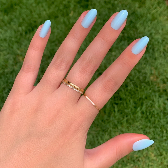 Hand wearing Honest & True | Almond | Medium serene blue medium almond shaped press-on nails outdoors with gold rings