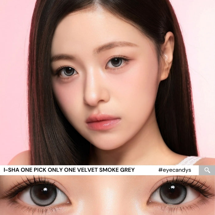 A woman with straight dark hair and smooth skin models the i-Sha One Pick Only One Velvet Smoke Grey colored contacts by i-Sha, featuring a natural-looking grey shade. A close-up below highlights her eyes, showcasing the velvet smoke grey contacts. The image has a pink background and includes product details.