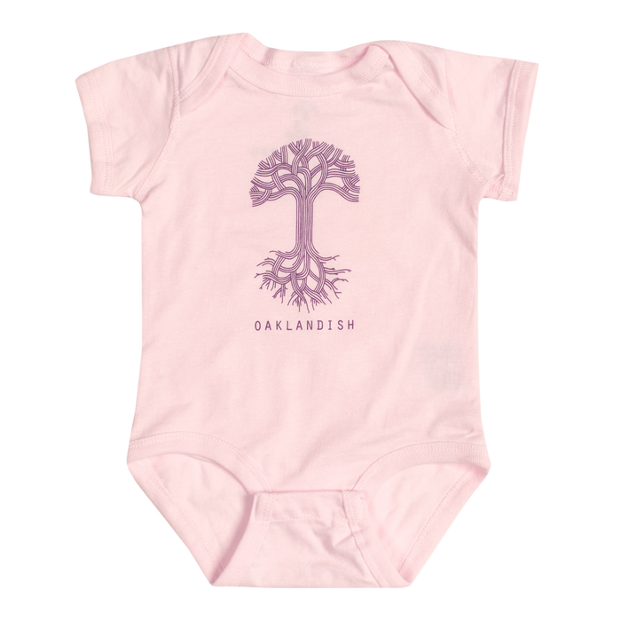 The Infant Oaklandish Classic Logo One-Piece by Oaklandish is a pink, short-sleeve baby romper made from 100% cotton. It showcases a line-drawn image of a tree with intricate branches and roots at the center, with "OAKLANDISH" prominently printed in bold capital letters below the tree. The onesie is displayed on an unadorned white background.