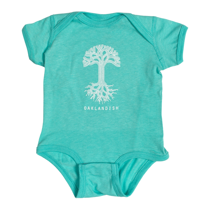 The Infant Oaklandish Classic Logo One-Piece by Oaklandish is a teal, 100% cotton short-sleeve romper featuring a round neckline and snap closures at the bottom. It showcases a white graphic of a tree with roots extending downward, with "OAKLANDISH" printed in white capital letters below the tree.