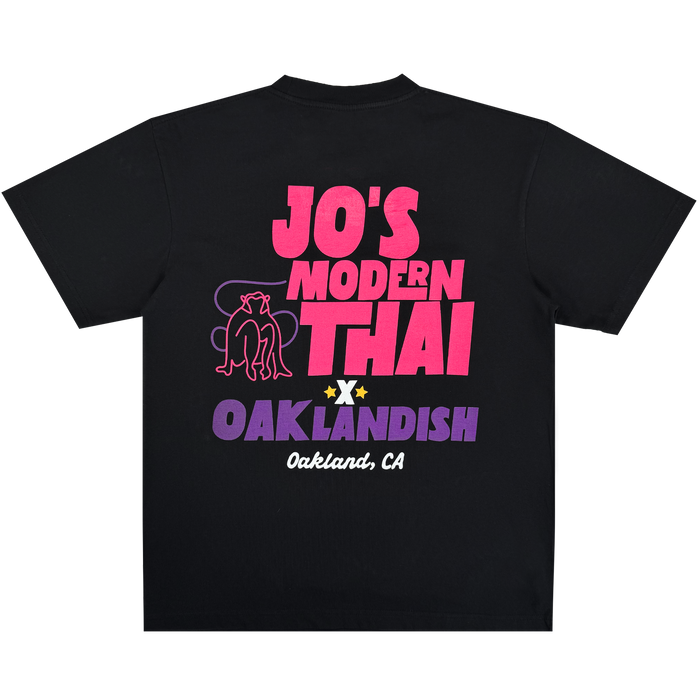 Introducing the Jo’s Modern Thai X Oaklandish Tee by Other: a black, heavy-weight t-shirt featuring vibrant pink and purple “Jo’s Modern Thai” text and an illustration of two seated panthers, with “Oaklandish” and “Oakland, CA” at the bottom. This collaborative design is centered on the back of the shirt.