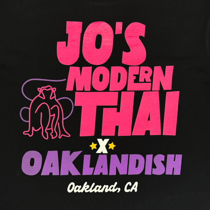 Introducing the Jo’s Modern Thai X Oaklandish Tee by Other: a black heavyweight t-shirt featuring bold pink and purple “Jo’s Modern Thai x Oaklandish, Oakland, CA” text, accented with a pink-outlined monkey illustration and yellow stars. This collaborative tee celebrates creative connections on a striking black background.