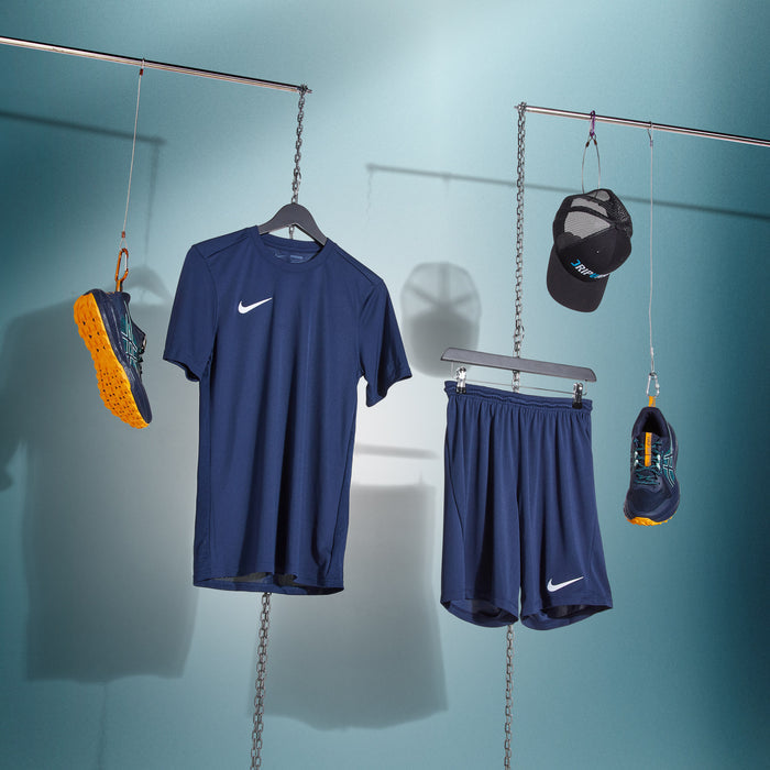 Navy athletic outfit with Nike shoes and cap hanging on a rack against a blue background