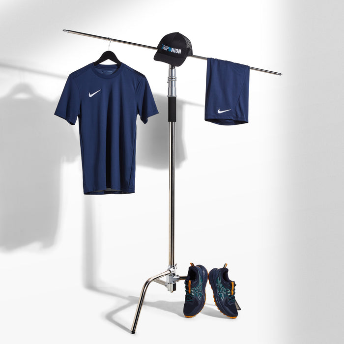 Navy athletic outfit with shirt, shorts, and shoes on a stand against a white background