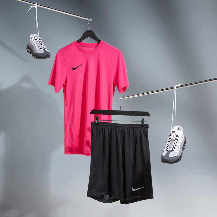 Pink sports shirt, black shorts, and white sneakers on a gray background