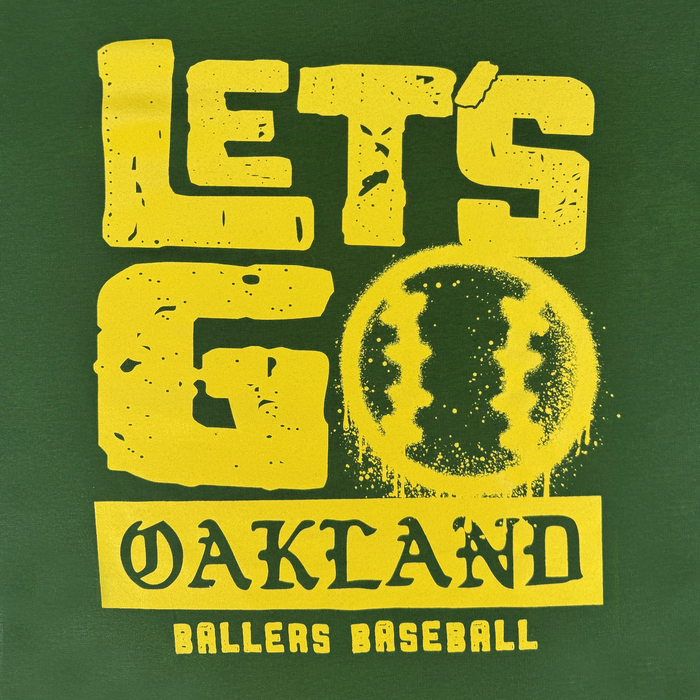 The Let's Go Oakland Tee by Oakland Ballers features a green background, bold distressed yellow "LET'S GO" over a baseball graphic, and "OAKLAND BALLERS" celebrating Oakland’s new pro Pioneer League baseball team. "BALLERS BASEBALL" in yellow at the bottom.
