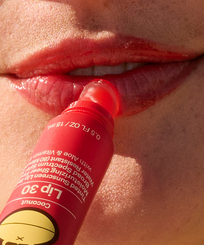Close-up of lips applying Sun Bum Heat Wave SPF 30 Moisturizing Lip Balm with a tinted red balm stick.