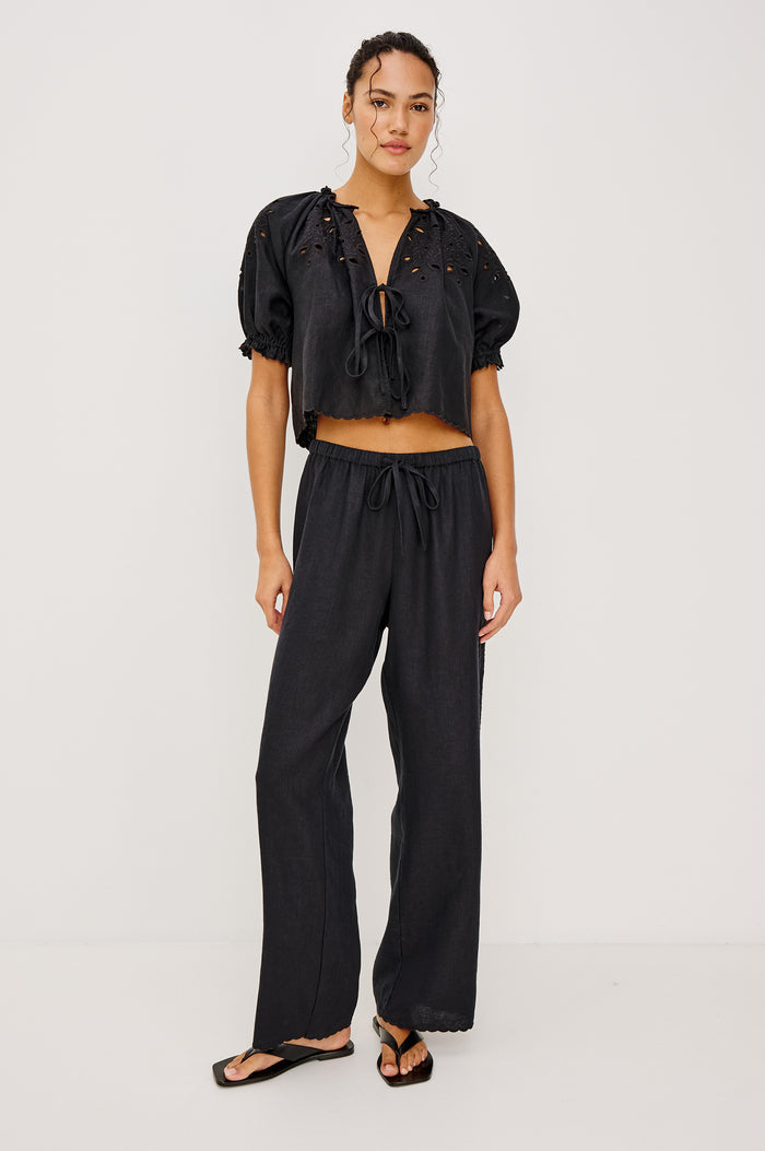 Lizbeth Milkmaid Top in Linen With Floral Eyelet Cutwork Plunging Tie-Front V-Neckline Front Ties Relaxed FIt Short Puff Sleeves in Black Ctolorway - Full Body Front View Featured on Model