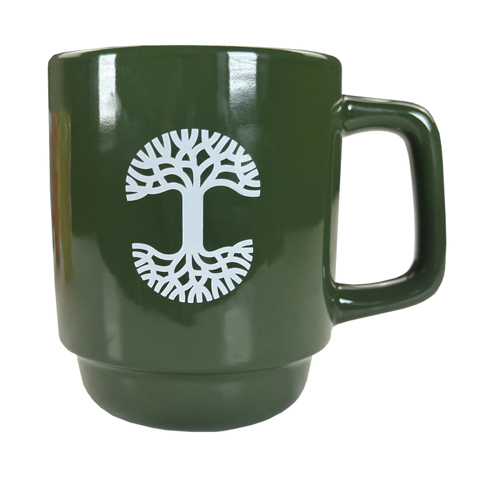 The Oaklandish Logo Stack Mug is a glossy green ceramic mug with a large handle and a white tree design. Its mirrored branches and roots stand out, while the stackable design adds style and practicality. Perfect for any kitchen.