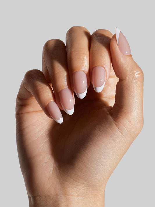 Hand with French Tip press-on nails on a light gray background