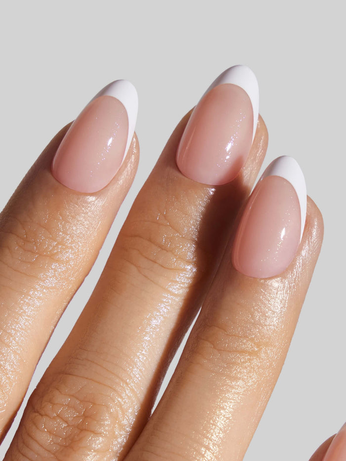 Close-up of a hand with French Tip press-on nails on a neutral background