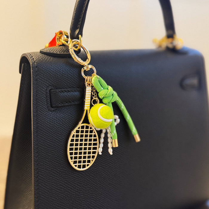 Ellison+Young Match Point tennis bag charm with sporty gold, neon accents, racket, and ribbon details for tennis enthusiasts.