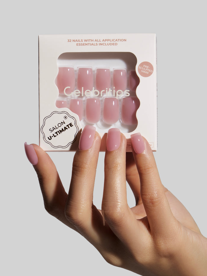 Hand with pink nails holding a package of 'Celebritips' nail extensions.