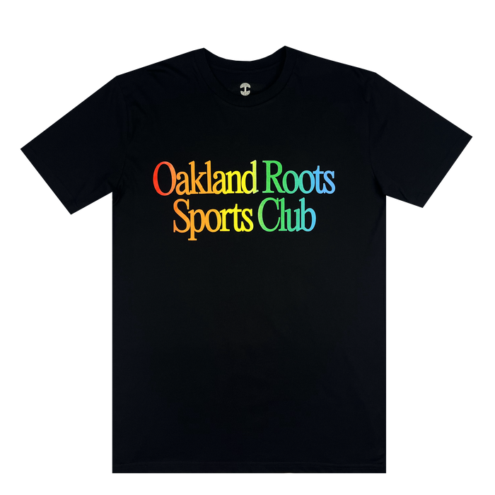 The More Than Soccer Tee by Oakland Roots SC is a black Classic fit t-shirt showcasing "Oakland Roots Sports Club" on the front in rainbow-colored letters. The vibrant hues transition through red, orange, yellow, green, blue, and purple from left to right. This social good tee features short sleeves and a round neckline.