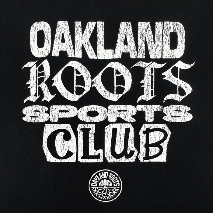 The Multi Text SS Tee by Oakland Roots SC features bold, stylized white text reading “OAKLAND ROOTS SPORTS CLUB” on a black background, above a circular Oakland Roots logo with the club name and signature tree graphic.
