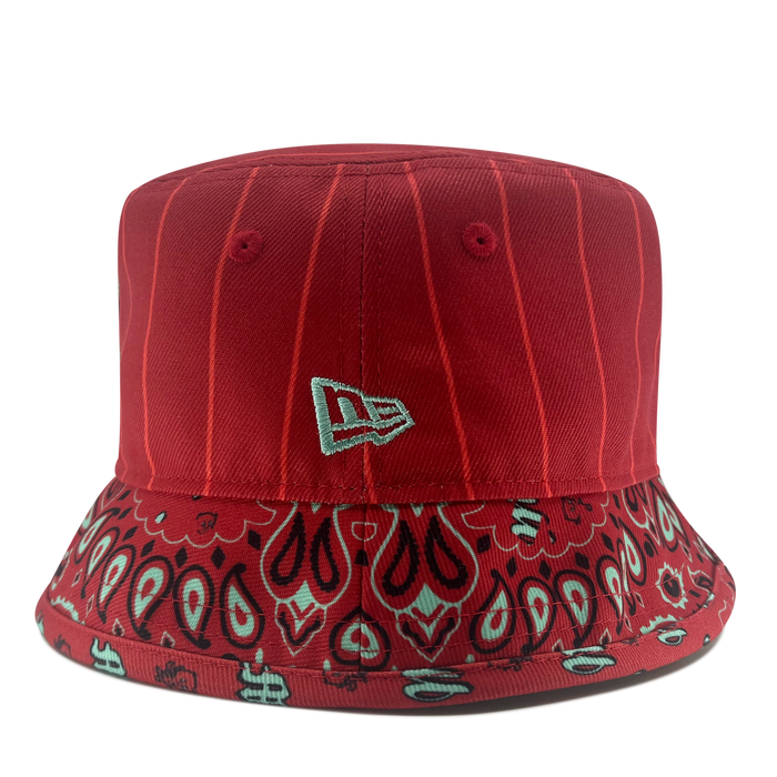 Introducing the New Era Diablos Paisley Bucket by Retail Vendors: a red polyester hat featuring white pinstripes on the crown and a bandana-inspired pattern around the brim. The design includes paisley and abstract floral elements in shades of white and black, complemented by a small, white embroidered logo on the front.