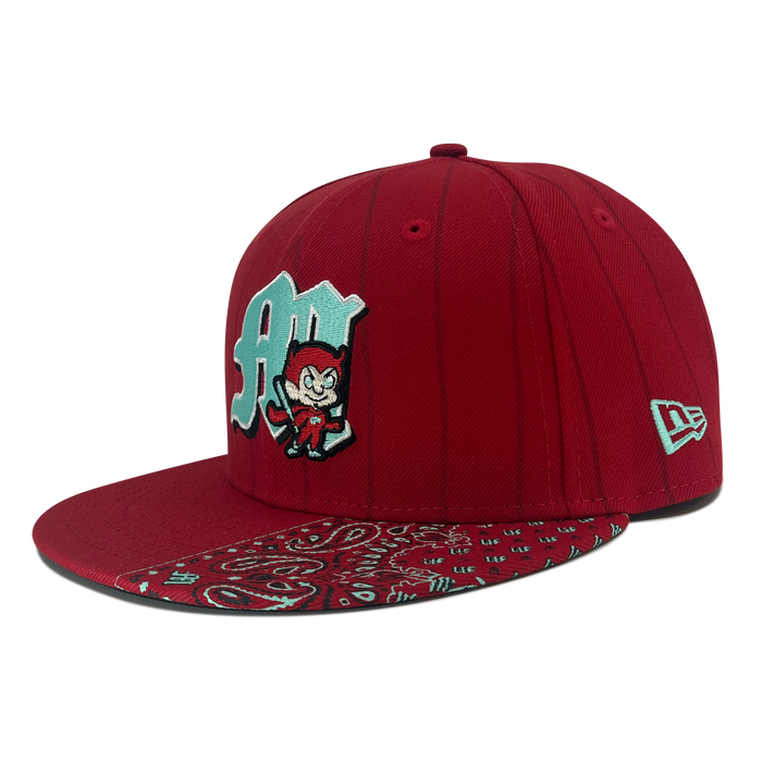 The New Era Diablos Pinstripe 59FIFTY Cap from Other features a vibrant red fitted design with vertical pinstripes. The front is adorned with a light blue “A” and a cartoon devil graphic, while the flat brim displays an eye-catching red and blue paisley bandana pattern. The cap is finished with the classic white New Era logo embroidered on the side.