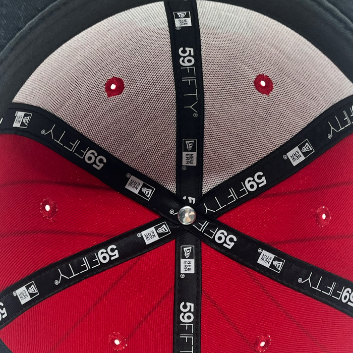 Close-up of the interior top of an Other New Era Diablos Pinstripe 59FIFTY Cap, featuring black branded taping, six stitched panels in red and gray fabric, white eyelets, and a silver button at the center.