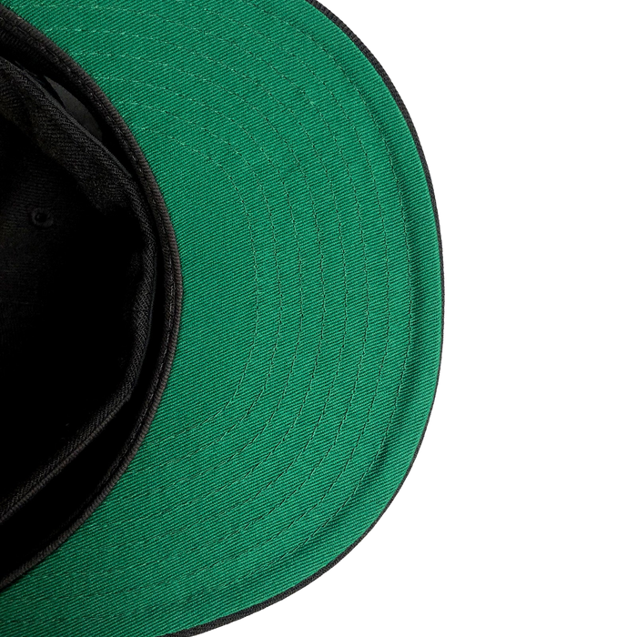 A close-up of a New Era Oakland Roots SC 59FIFTY Fitted Cap with a black underside. The image captures the cap lying on its side, revealing the green fabric of the visor and part of the black interior. The texture and stitching are clearly visible, indicating its affiliation with Oakland Roots SC against a clean, white background.