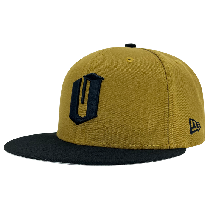 Introducing the New Era Official 59FIFTY Fitted Cap from Other—a bold mustard yellow snapback featuring a striking black brim and a prominent black “U” logo on the front, finished with a small New Era emblem stitched on the side. Inspired by classic Oaklandish fitted cap style, this standout design brings vibrant energy against a plain white backdrop.