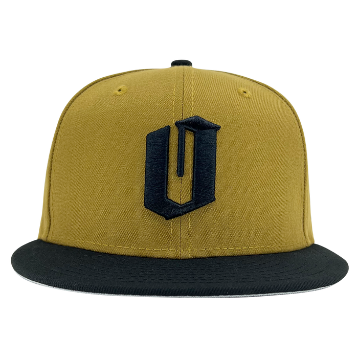 A yellow New Era Official 59FIFTY Fitted Cap by Other features a flat black brim and a prominent, stylized black letter “U” embroidered on the front panel. The cap is displayed head-on and centered against a plain white background.