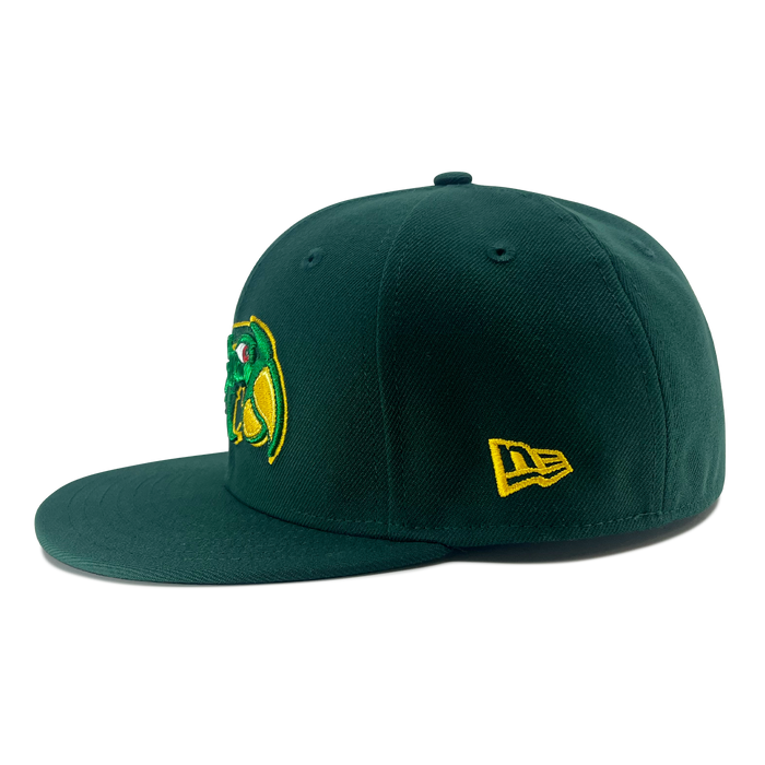 The New Era Pericos 59FIFTY Cap by Other features a dark green design with a flat brim and structured crown. It displays an embroidered yellow New Era logo on the side, while the front showcases a green and yellow mascot graphic set against a white background. For added authenticity, this fitted cap also includes the iconic LMB logo.