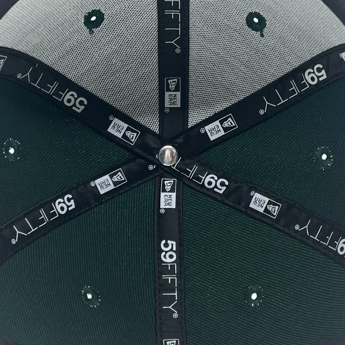Close-up of the interior of a green and gray New Era Pericos 59FIFTY Cap by Other, highlighting its six-panel construction with vent holes, a central metal button, and black taping featuring white “59FIFTY” and New Era branding.