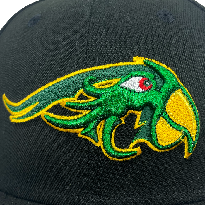 The New Era Pericos ALT 59FIFTY Cap by Other is a black fitted cap showcasing a detailed, embroidered green and yellow creature with a red eye—resembling a stylized sea monster or dragon—prominently stitched on the front panel. The pronounced curves and sharp edges in the embroidery give this cap its bold and distinctive appearance.
