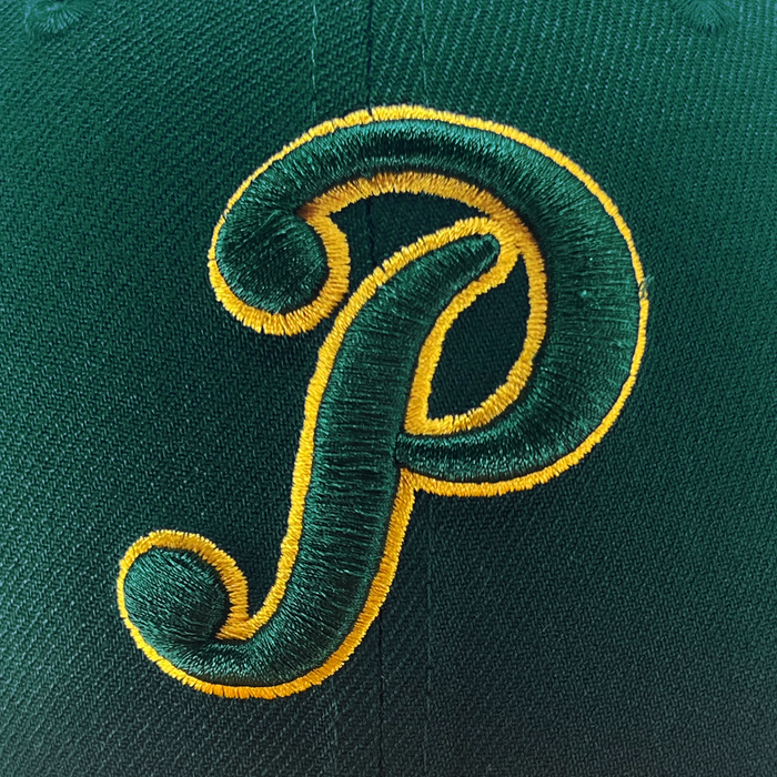 Close-up of the New Era Pericos Home 59FIFTY Cap in green fabric, showcasing a large, embroidered yellow and green letter “P” outlined in yellow at the center front. The iconic LMB logo accents the side, with crisp stitching and textured material visible throughout. This premium fitted cap by Other is designed for standout style and lasting comfort.