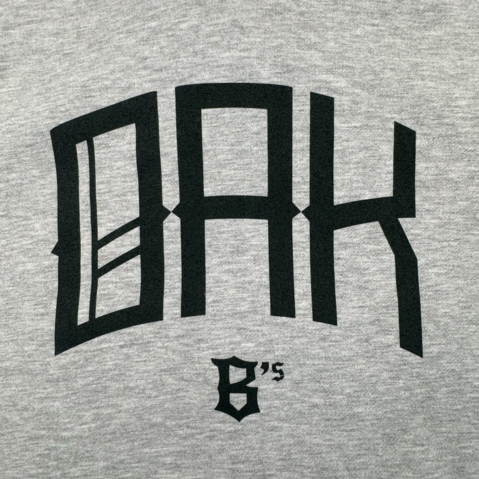 The OAK Ballers Hoodie by Oakland Ballers features gray fabric with large, bold black "OAK" text and "6’s" in smaller, sharp-angled gothic font—a tribute to the Oakland Ballers Pioneer League baseball team.