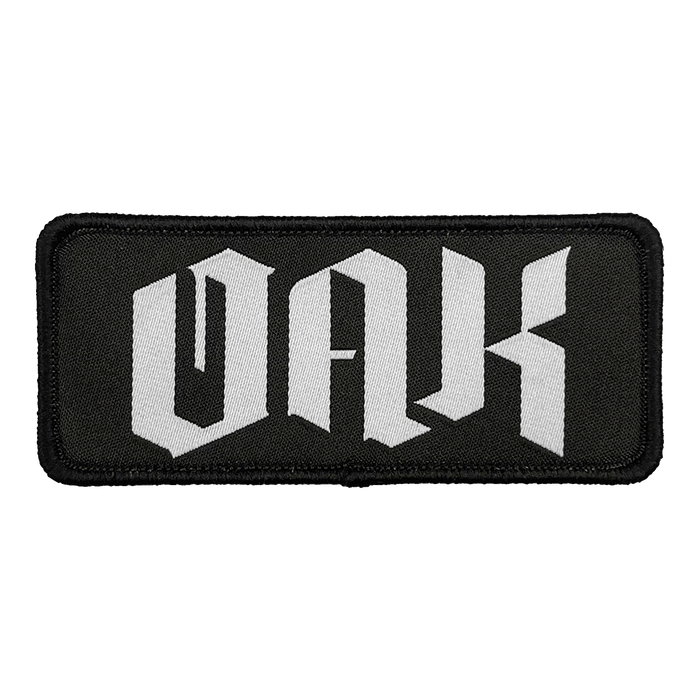 The OAK Official Patch by Oaklandish is a rectangular black emblem with a matching border and prominently displays the letters "OAK" in bold, white Gothic script. The intricate lettering evokes a medieval aesthetic, adding an element of classic elegance to your accessories. This embroidered iron-on patch offers a stylish touch to your collection.