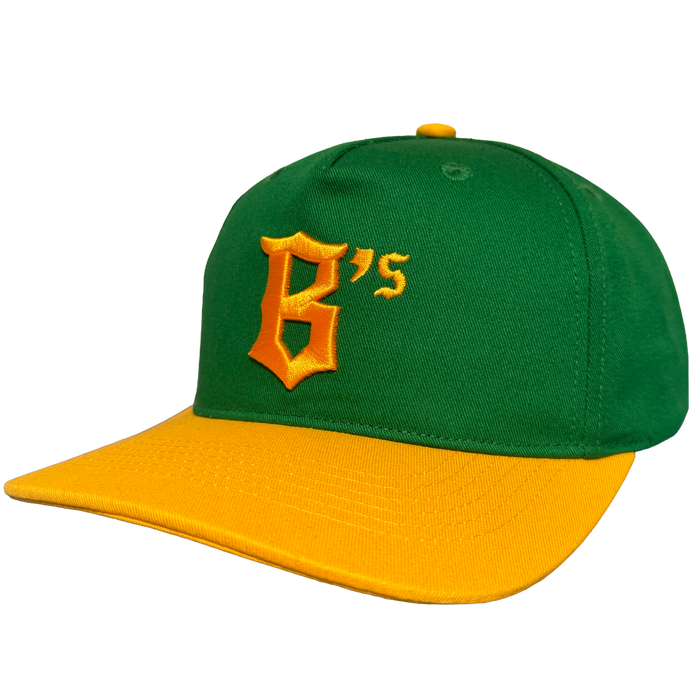 The Oakland Ballers 5 Panel Cap features a green snapback design with a yellow brim and top button, plus a large embroidered yellow "B’s" on the front. Shown against a plain white background. Brand: Oakland Ballers.