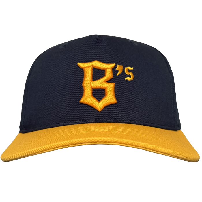 The Oakland Ballers 5 Panel Cap features a navy blue body, bright yellow brim, and a bold old English-style yellow "B's" on the front—perfect for any Oakland Ballers fan. Background is plain white.