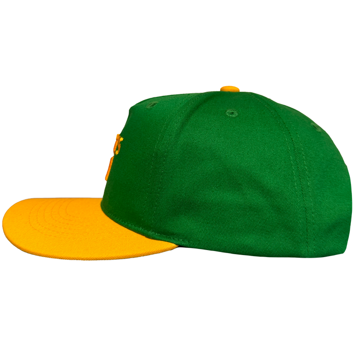 The Oakland Ballers 5 Panel Cap features a green body, flat bright yellow brim, and yellow top button, shown in side profile on a plain white background. Visible stitching and eyelets add to its classic baseball cap look.