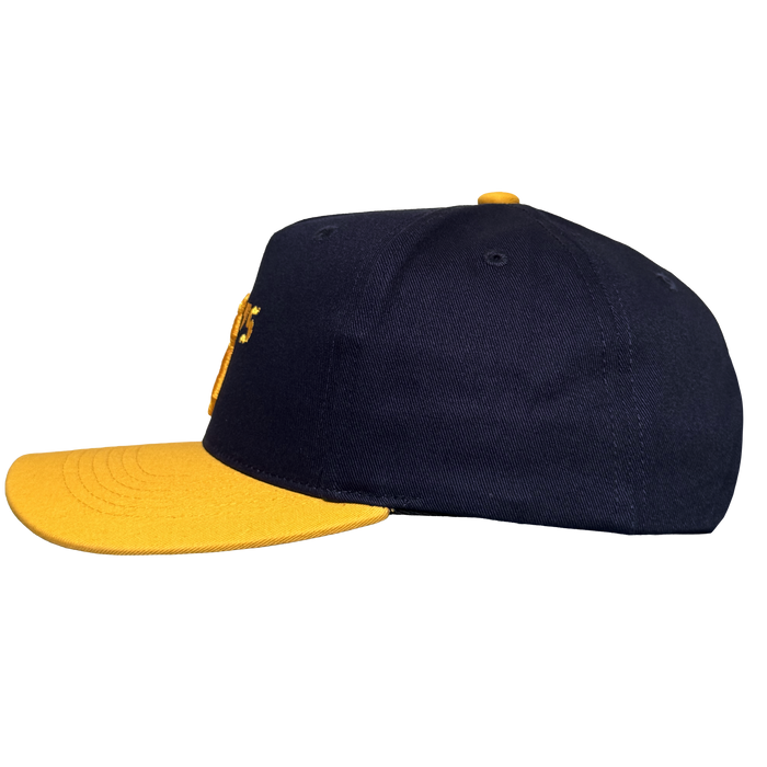 The Oakland Ballers 5 Panel Cap by Oakland Ballers features a navy blue snapback design, flat bright yellow brim, and matching yellow top button. Seen from the side on a white background, partial yellow embroidery appears on the front.